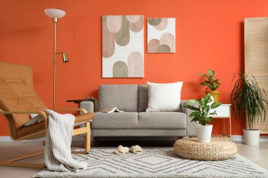 Gri koltuğu, koltuğu ve bitkileri olan şık bir oturma odası.