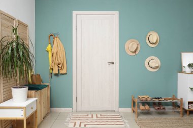 Ayakkabı standı, şapkası ve kapısı olan şık bir koridor.