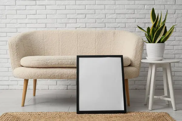 Kanepenin yanında boş resim çerçevesi olan modern oturma odası.