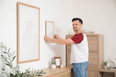 Evdeki ışık duvarında boş bir çerçeve asılı genç adam