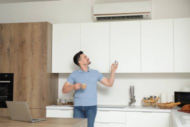 Kahveli yakışıklı adam mutfaktaki klimayı açıyor.