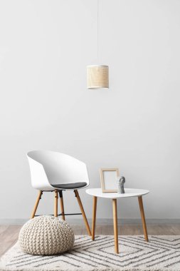 Sandalye, çerçeveli kahve masası, dekor ve beyaz duvarın yanındaki puf.
