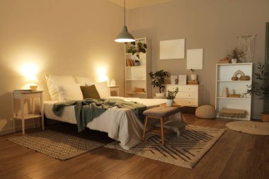 Karanlık yatak odasının içi, rahat yatağı, çiçekleri ve parlayan lambaları olan.