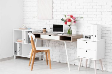 Güzel yıldız çiçekleri ve aydınlatma odasında modern dizüstü bilgisayarı olan şık bir iş yeri.