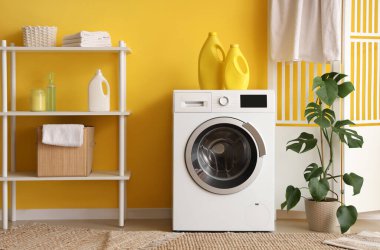 Çamaşır makinesi, deterjan ve raf ünitesi olan bir çamaşırhane.