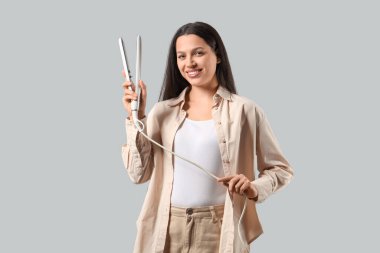 Beyaz arka planda saç düzleştiricisi olan güzel bir genç kadın.