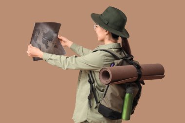 Genç bayan turist, bej arka plan haritasını inceliyor.