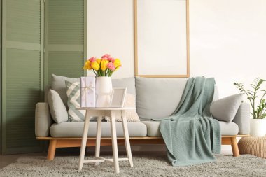 Anneler Günü için dekore edilmiş oturma odasının içinde kanepe, masa ve boş çerçeve var.