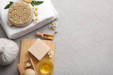 Ahşap tepsi, papatya çiçekleri, sabun çubuğu ve bal kasesi gri grunge arka planda, yakın plan.