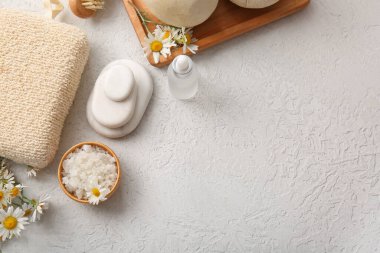 Spa taşları, deniz tuzu ve papatya çiçekli kase gri grunge arka plan, yakın plan.