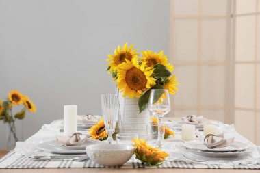 Tabakları, bardakları ve güzel ayçiçekleri olan zarif bir masa.