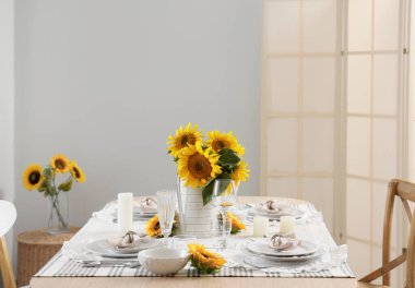 Tabakları, bardakları ve güzel ayçiçekleri olan zarif bir masa.