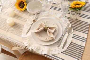 Tabaklarla servis edilen zarif masa, katlanmış peçete ve güzel ayçiçekleri, yakın plan.