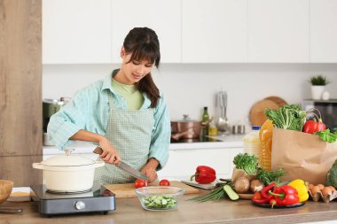 Mutfakta domates kesen genç bir kadın.