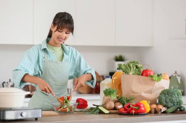 Mutfaktaki masada sebze salatası yapan genç kadın.