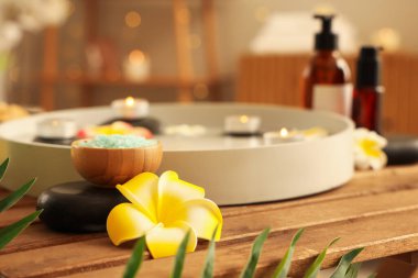 Mumlar, spa taşları, Plumeria çiçekleri, kozmetik ürünleri ve salonda masanın üzerinde deniz tuzu olan tabaklar.