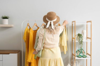 Soyunma odasında, elbise dolabının yanında genç bir kadın var.