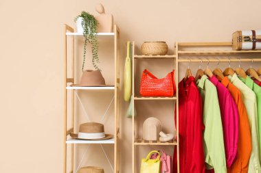 Giysi askısı ve raf ünitesi, bej duvarın yanında aksesuarlar.