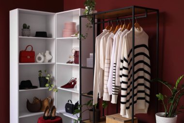 Giysi askısı, raf ünitesi ve bitkileri olan soyunma odasının içinde.