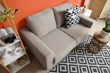 Gri kanepesi, masaları ve raf ünitesi olan şık bir oturma odası.