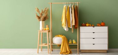 Koridorun içinde sonbahar kıyafetleri, çekmeceler ve balkabakları var.