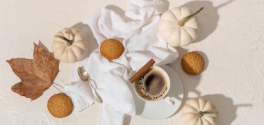 Bir fincan lezzetli balkabağı kahvesi, sonbahar süslemeleri ve grunge beyaz arka planda kurabiyeler.