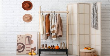 Koridorun içinde sonbahar kıyafetleri, katlanan ekran ve balkabakları var.