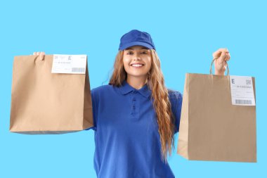 Mavi arka planda kağıt torbaları olan kadın kurye.