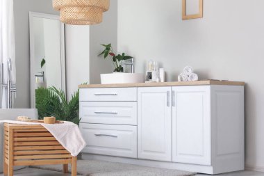 Beyaz tezgahlarda ve aynalarda lavabo kasesi olan hafif bir banyo.