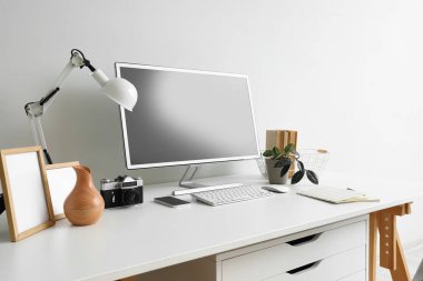 Modern bilgisayar ve ışık duvarının yanında fotoğraf makinesi olan şık bir iş yeri.