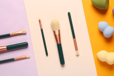Renkli arkaplanda makyaj süngerleri ve fırçalar