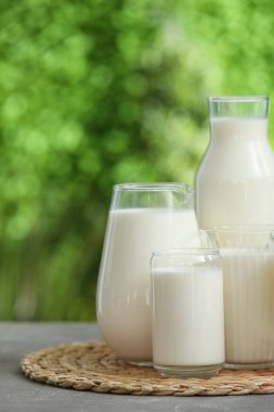 Gri masada bardaklar ve bir şişe taze süt.