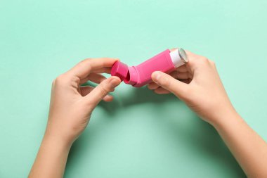 Turkuaz arka planda astım spreyli çocuk elleri