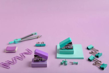 Okul malzemeleri ve mor arka planda zımbalar.