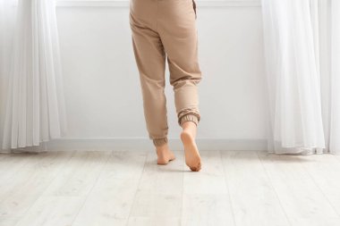 Çıplak ayaklı kadın, odada, arka planda, lamine zeminde yürüyor.