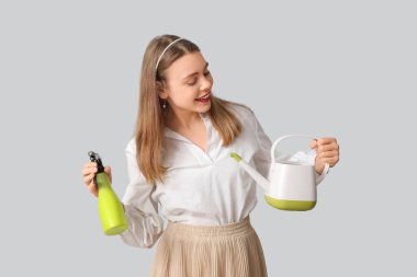 Sulama kabı ve gri arka planda su püskürtücüsü olan güzel genç bir kadın.