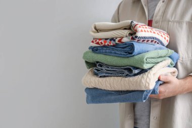 Arka planda giysi yığını olan genç adam, yakın plan.