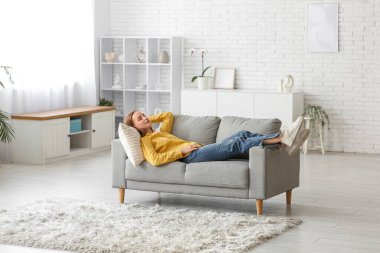 Oturma odasındaki kanepede dinlenen genç kadın.