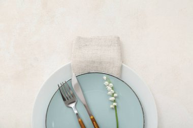 Tabakları, peçetesi, çatal bıçak takımı ve çiçekleri olan güzel bir masa.