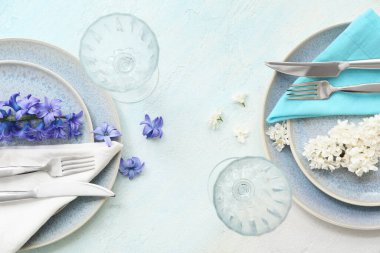 Temiz tabaklar, çatal bıçak, peçete, bardaklar ve çiçekli güzel bir kompozisyon.