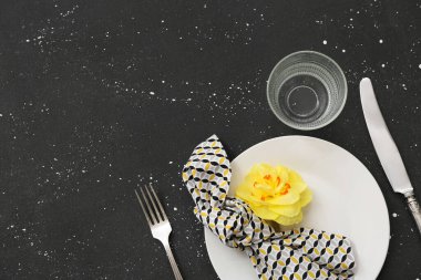 Tabak, peçete, cam, çatal bıçak ve çiçekli güzel bir masa.