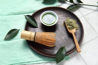 Bir kase kibrit çayı, beyaz fayans zemininde toz ve ahşap kepçe.