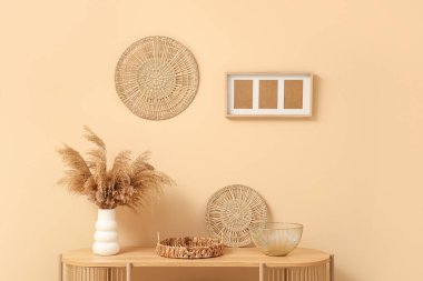 Bej duvarın yanında farklı dekorları olan ahşap raf ünitesi.