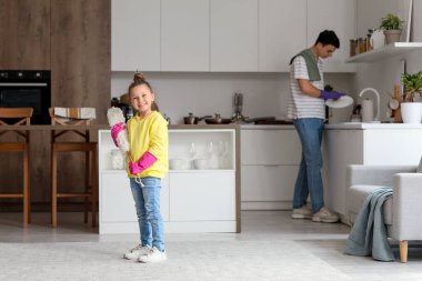 Küçük tatlı bir kız, yanında toz bezi ve babası var.