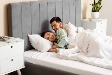 Kocasıyla yatak odasında yatan genç bir kadın.