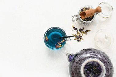 Çaydanlık, mavi organik çay ve beyaz arka planda kavanozda bezelye çiçeği çayı.
