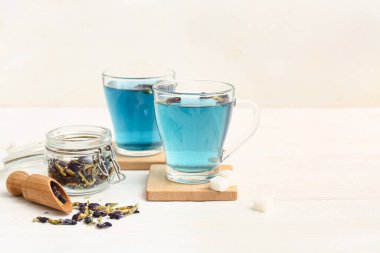 Kelebekli kavanoz bezelye çiçeği çayı ve beyaz arka planda mavi organik çay, yakın plan.