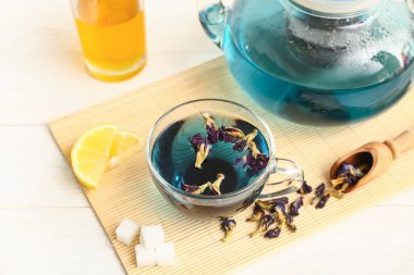 Kurutulmuş bezelye çiçeği çayı, bambu hasırı ve beyaz arka planda mavi organik çay, yakın plan.