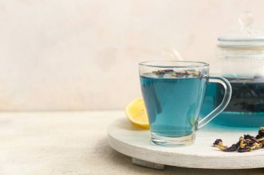 Beyaz ahşap tepside bir fincan kelebek arkaplanda bezelye çiçeği çayı, yakın plan.