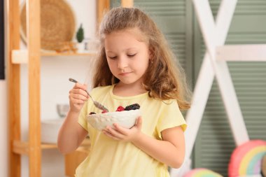 Mısır gevreği, yoğurt ve böğürtlen dolu küçük tatlı bir kız.